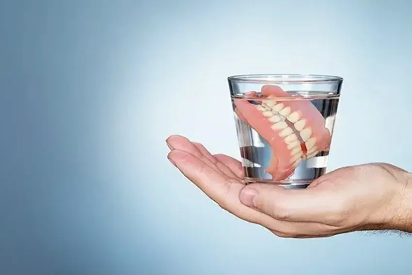 Traditional dentures sitting in a glass cup