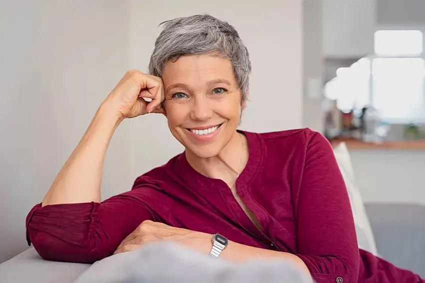 mature woman relaxing on her couch, showing off her amazing smile