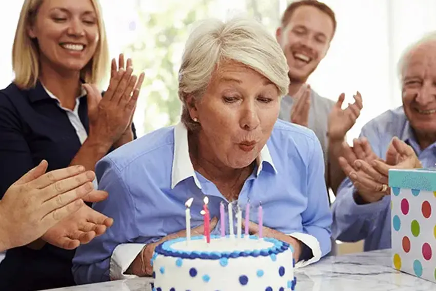 Grandmother blowing out her candles on her birthday cake
