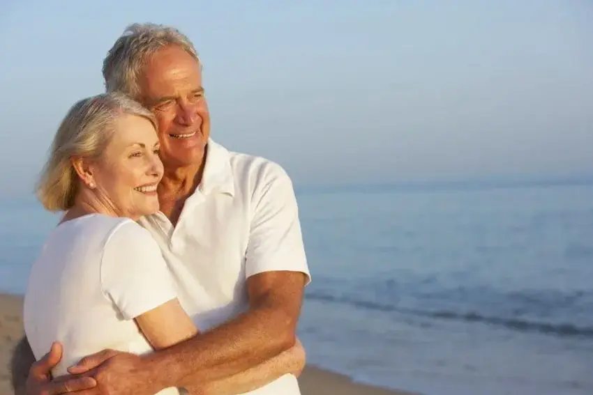 Senior couple looks out at the sea while walking on the beach