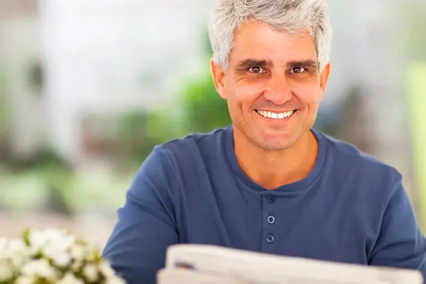 Middle aged man reading the newspaper at home