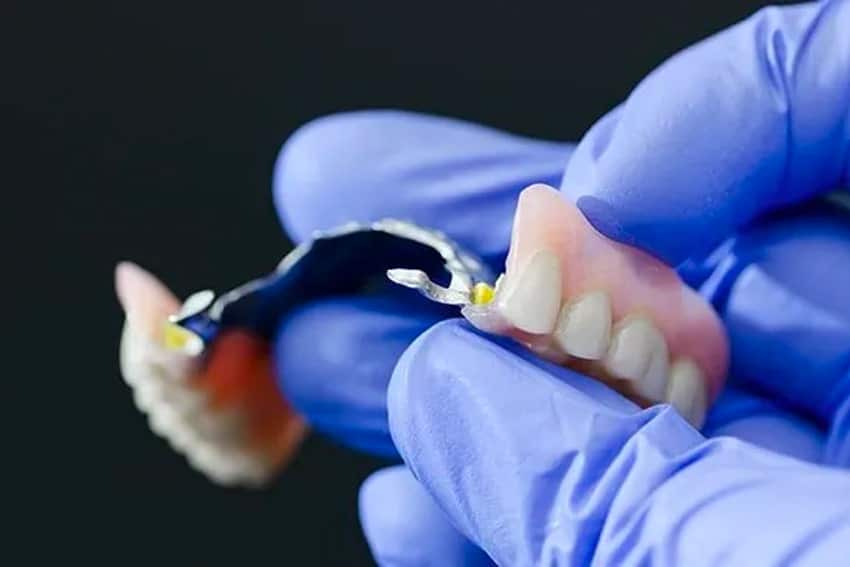 Gloved hand inspected a broken denture