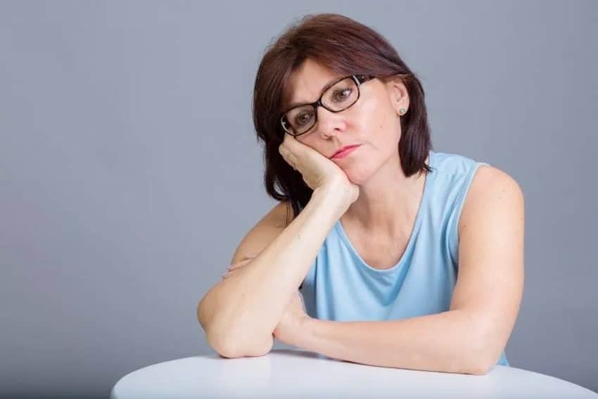Woman in glasses sits and contemplates her thoughts