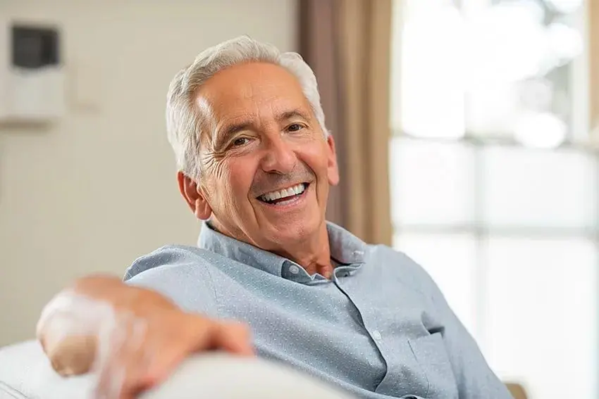 Why Dentures Could Be the Best Smile of Your Life_-min senior man relaxes on his couch at home